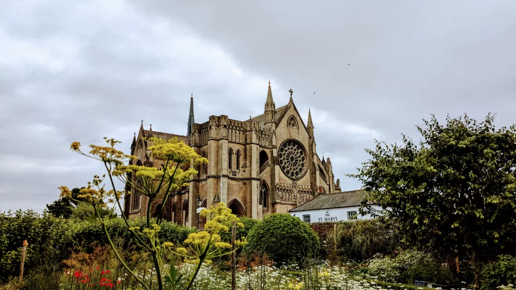 Arundel cathedral church with planting in the foreground and a moody, cloudy sky.