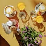 A bird's eye view of two coffees and two orange juices on a brightly lit table.