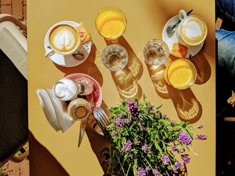 A bird's eye view of two coffees and two orange juices on a brightly lit table.