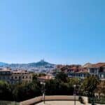 Panoramic view of Marseille, France with colourful city buildings and Notre-Dame de la Garde basilica in the background.