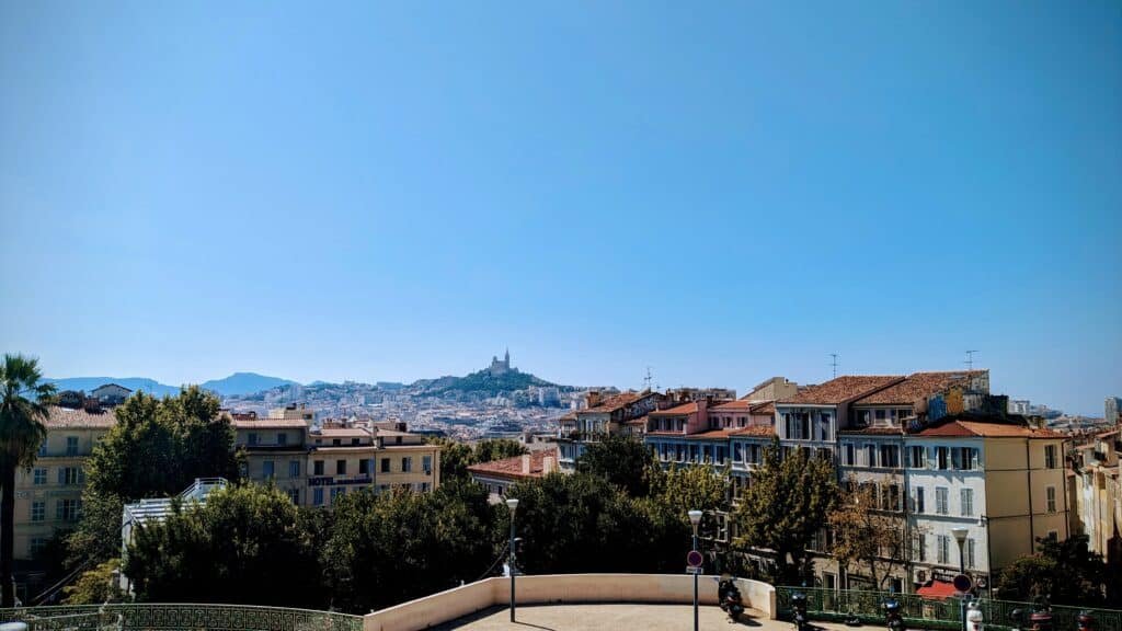 Blue sky with a cathedral in the background. Colourful houses are in the foreground. Its the view from Marseille train station, and your first view after taking the Eurostar to Marseille.