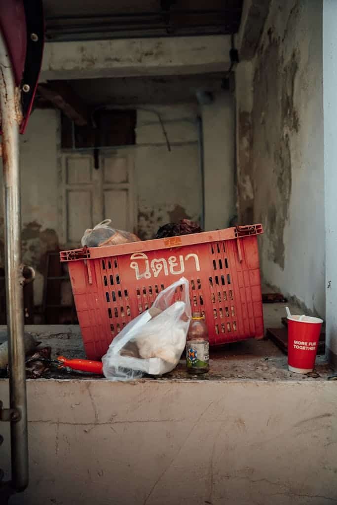 A street shot depicting urban decay with a vibrant red crate and discarded items in Bangkok.