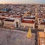 A stunning aerial view of Lisbon's cityscape with a festive Christmas tree in Praça do Comércio at sunset.