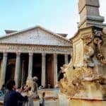 The white stone pantheon rises up behind an ornate stone waterfall, with some tourists in between them