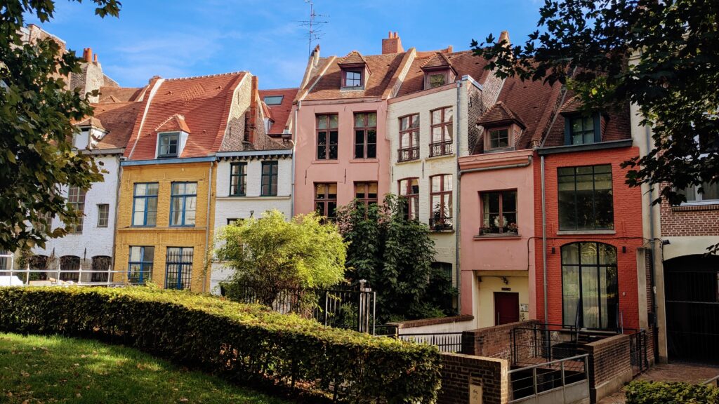 Colourful historic European townhouses with vibrant facades, charming architecture, and lush greenery under a blue sky, showcasing picturesque cityscapes ideal for travel photography.