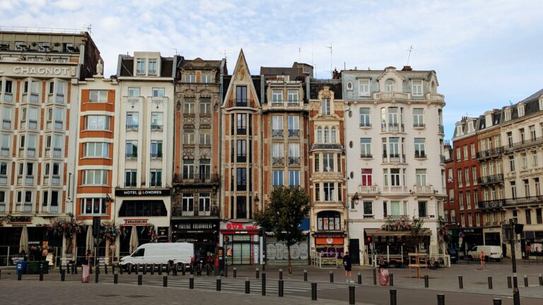 Charming Parisian buildings with classic architecture line a bustling street scene, featuring cafes, shops, and pedestrians, capturing the essence of a vibrant Paris neighbourhood for travel enthusiasts.