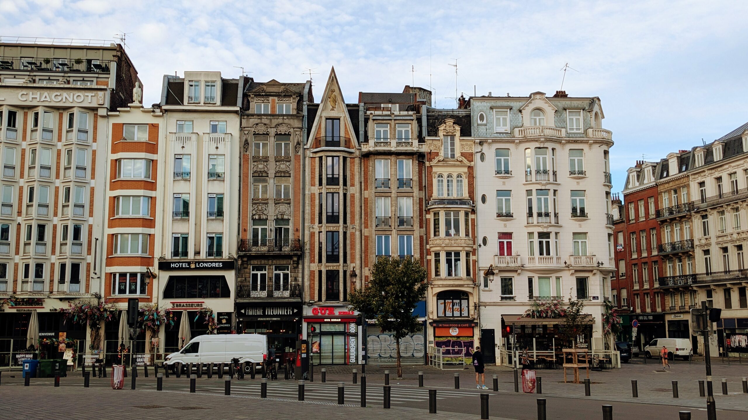 Charming Parisian buildings with classic architecture line a bustling street scene, featuring cafes, shops, and pedestrians, capturing the essence of a vibrant Paris neighbourhood for travel enthusiasts.