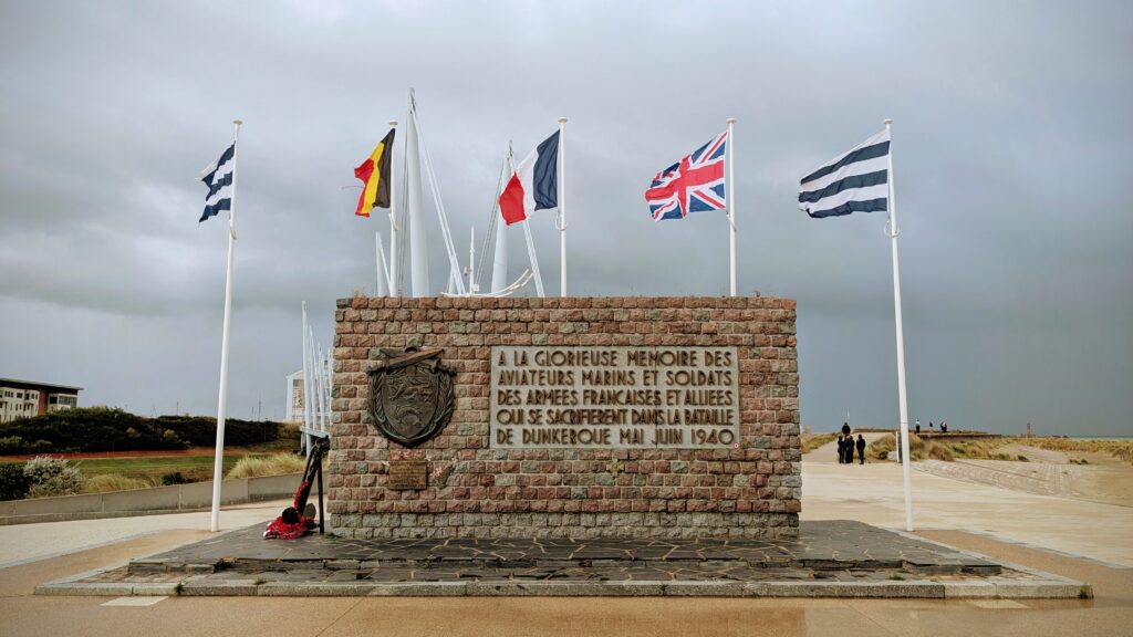 Flags flying at Dunkerque memorial site, commemorating French and Allied sailors who fought and sacrificed their lives in the Battle of Dunkirk, May-June 1940, on a cloudy day.