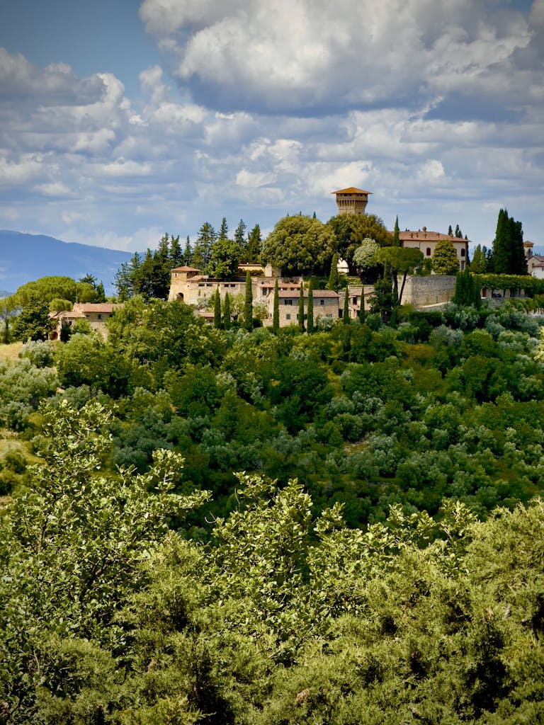 Stunning aerial view of a historic castle surrounded by lush greenery in Tuscany, Italy.