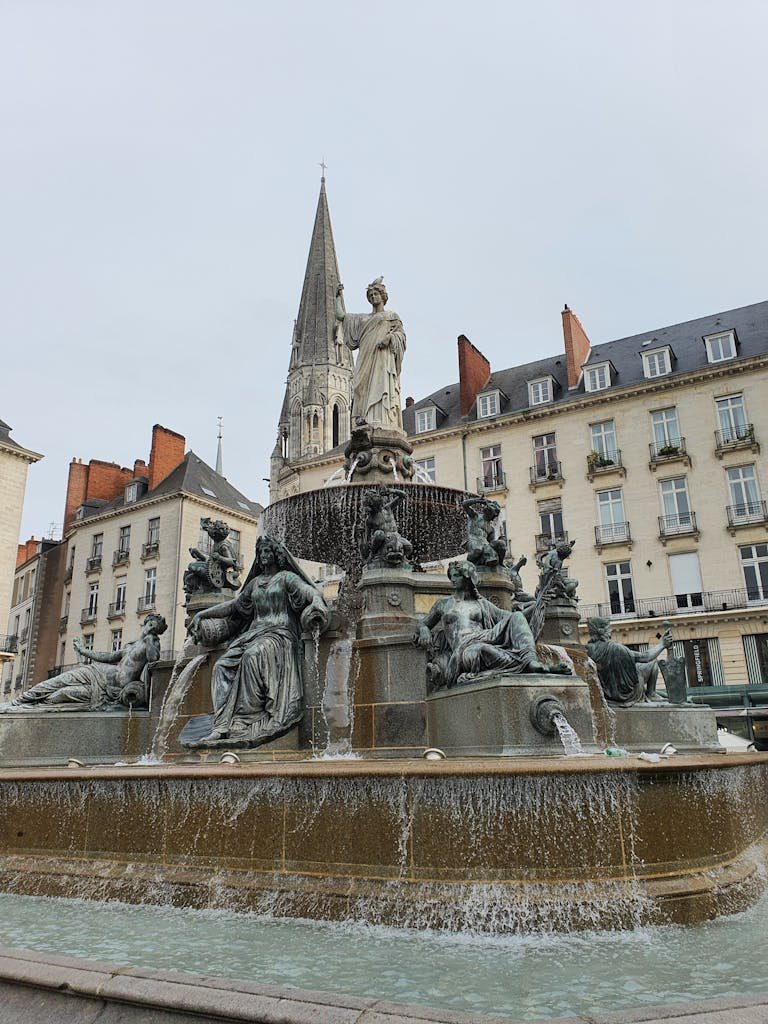 Beautiful city fountain with statues in Nantes, France, against historic architecture.