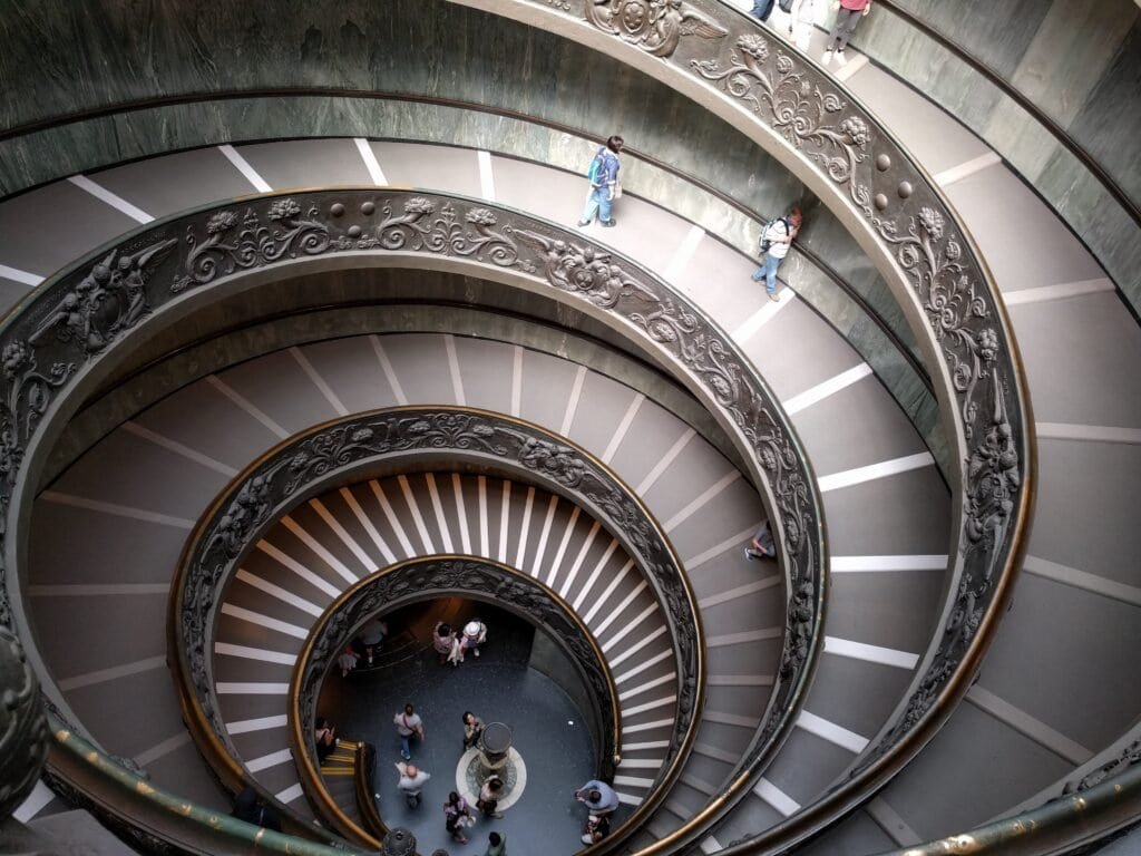 A detailed view of a stunning, ornate spiral staircase with intricate metalwork and elegant design, showcasing architectural beauty and craftsmanship in a historic building.