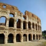 Iconic Roman Colosseum in Rome showcasing its historic arches and ancient architecture under a clear blue sky.