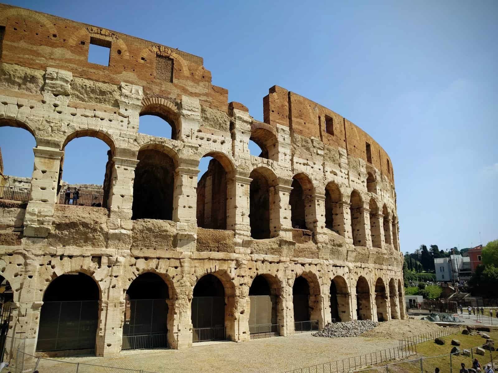 Iconic Roman Colosseum in Rome showcasing its historic arches and ancient architecture under a clear blue sky.